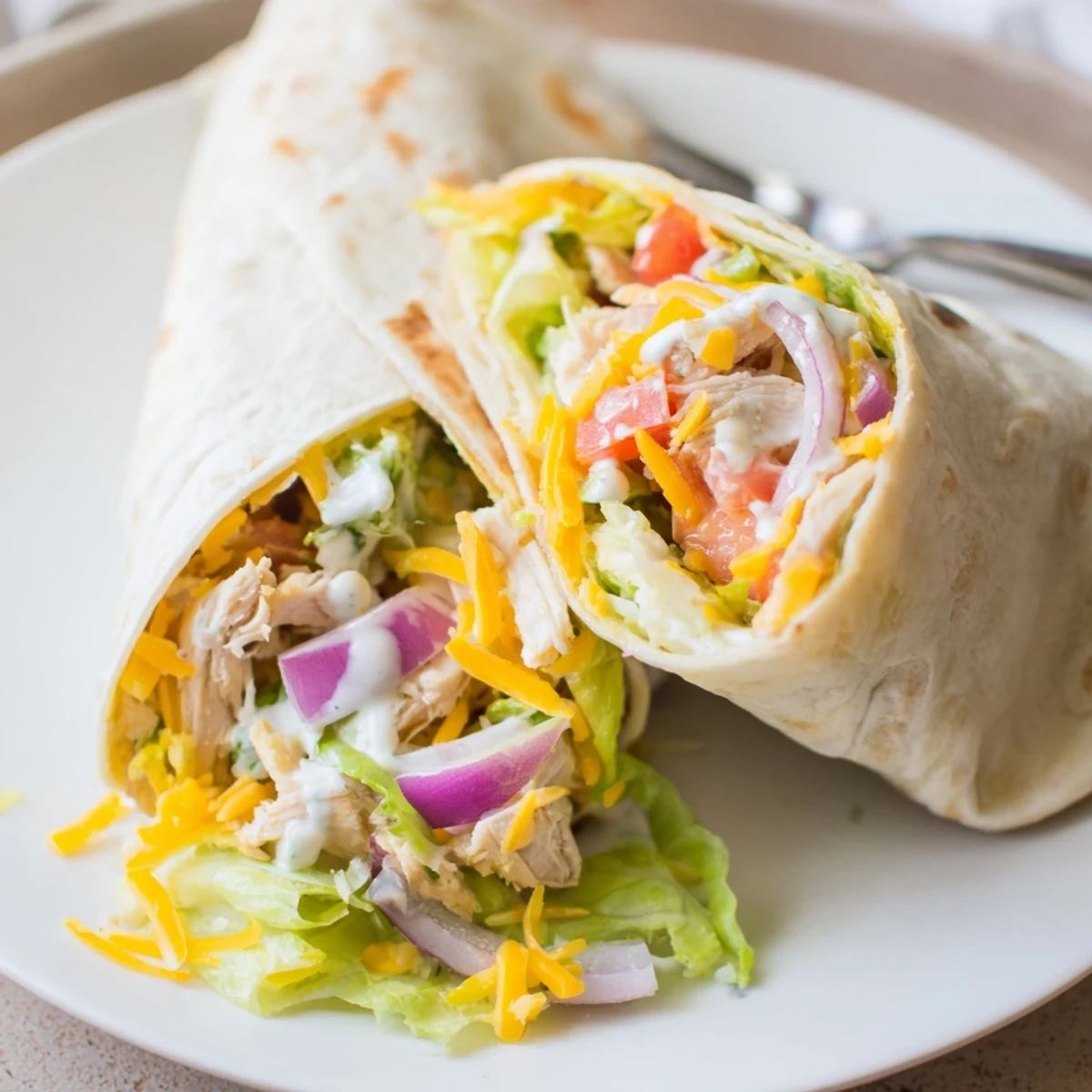 Warm Cheesy Garlic Chicken Wraps sliced in half, gooey cheese stretching.