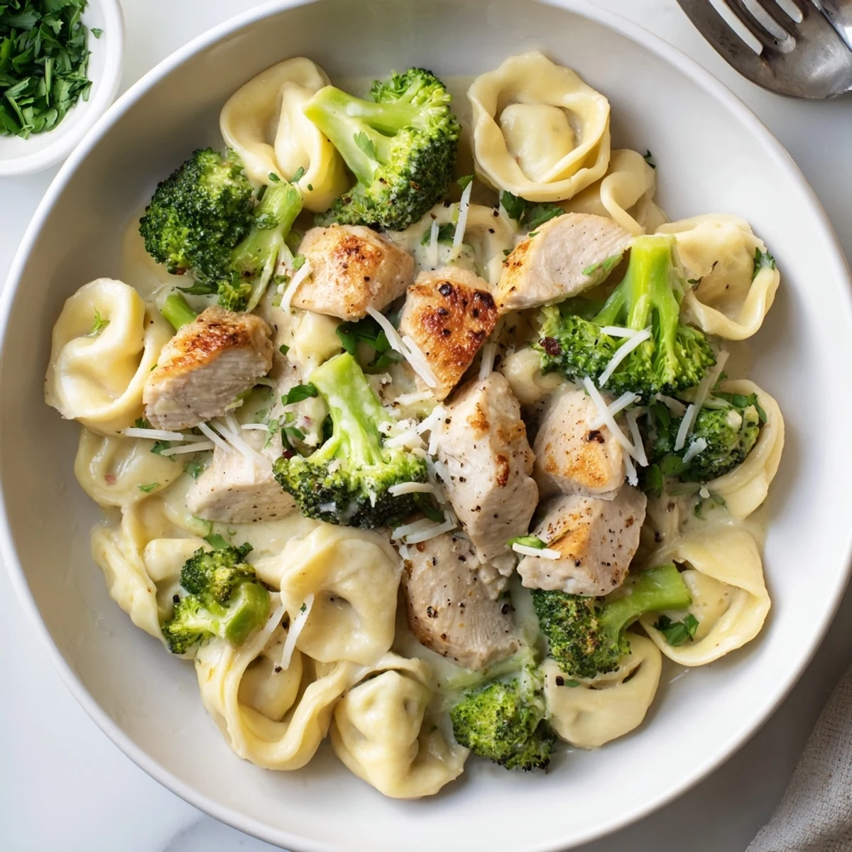 Creamy Garlic Parmesan Tortellini Chicken Broccoli plated with parsley, melted Parmesan, fork ready