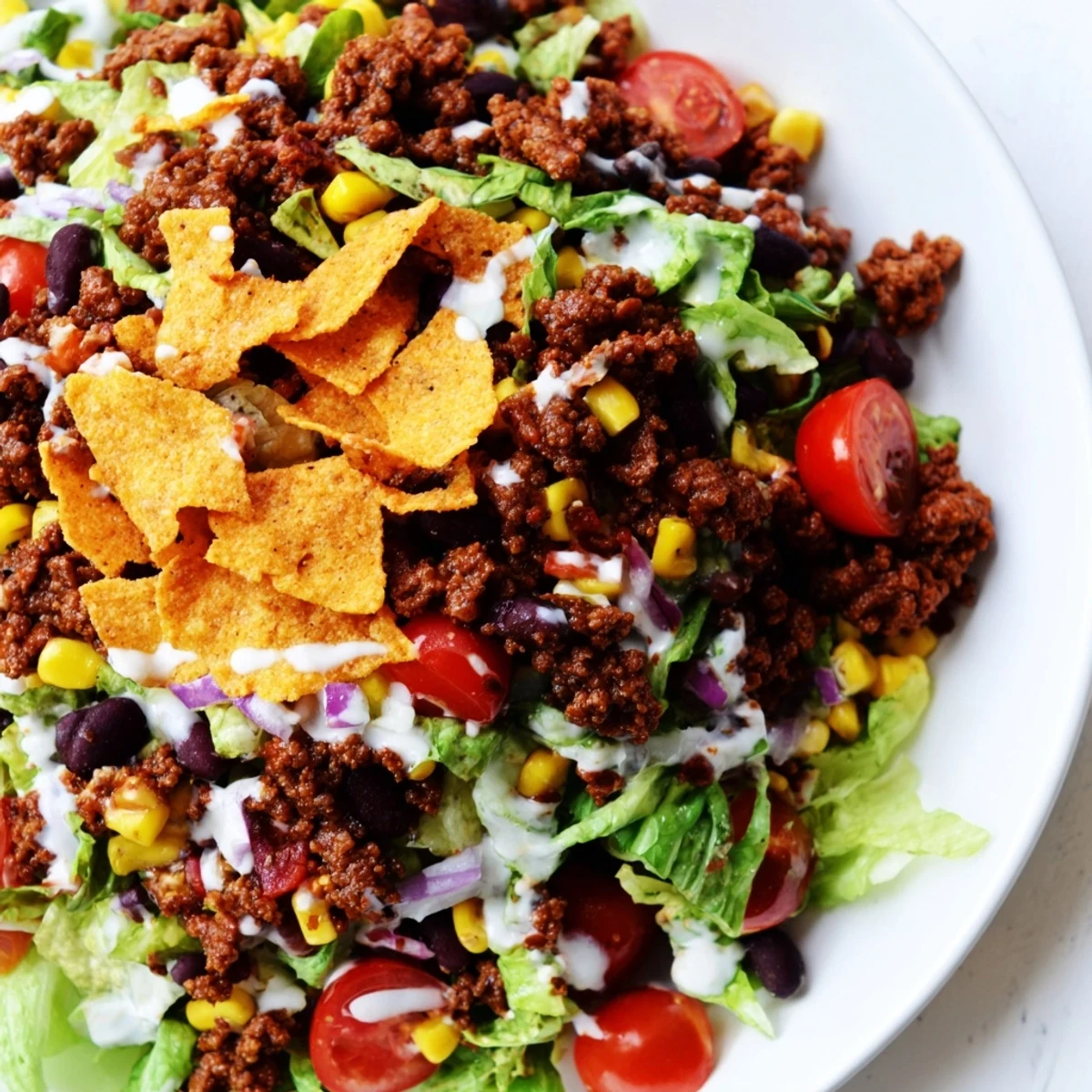 Bowl of Simple Doritos Taco Salad topped with cheddar, cherry tomatoes, and beans