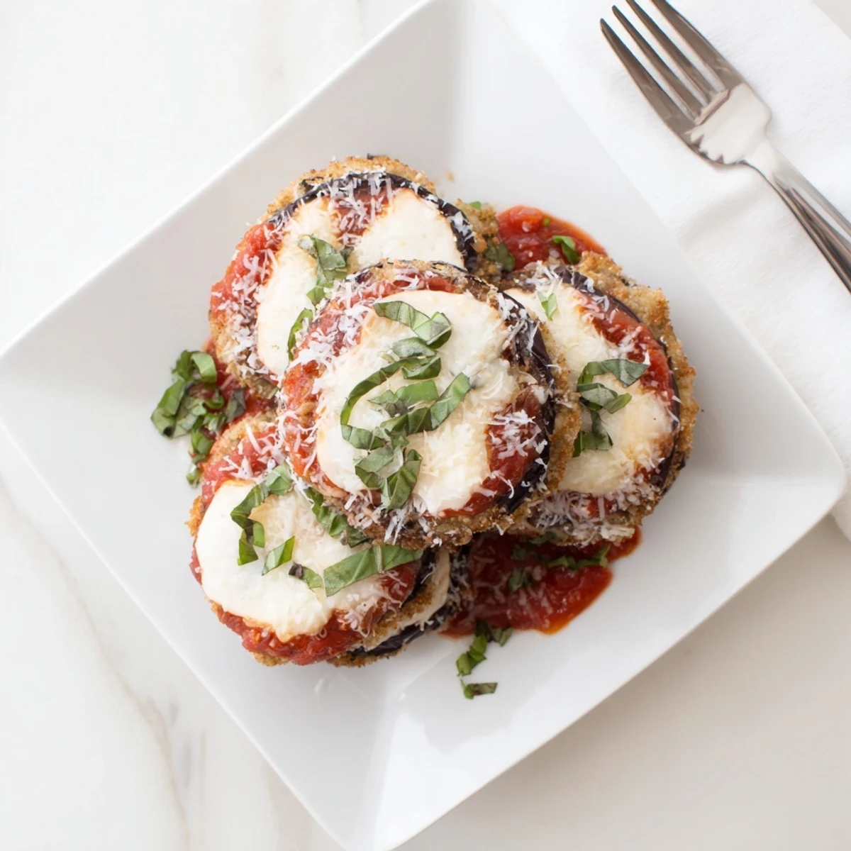 Homemade eggplant parmesan with golden breadcrumbs, rich marinara, and fresh basil garnish