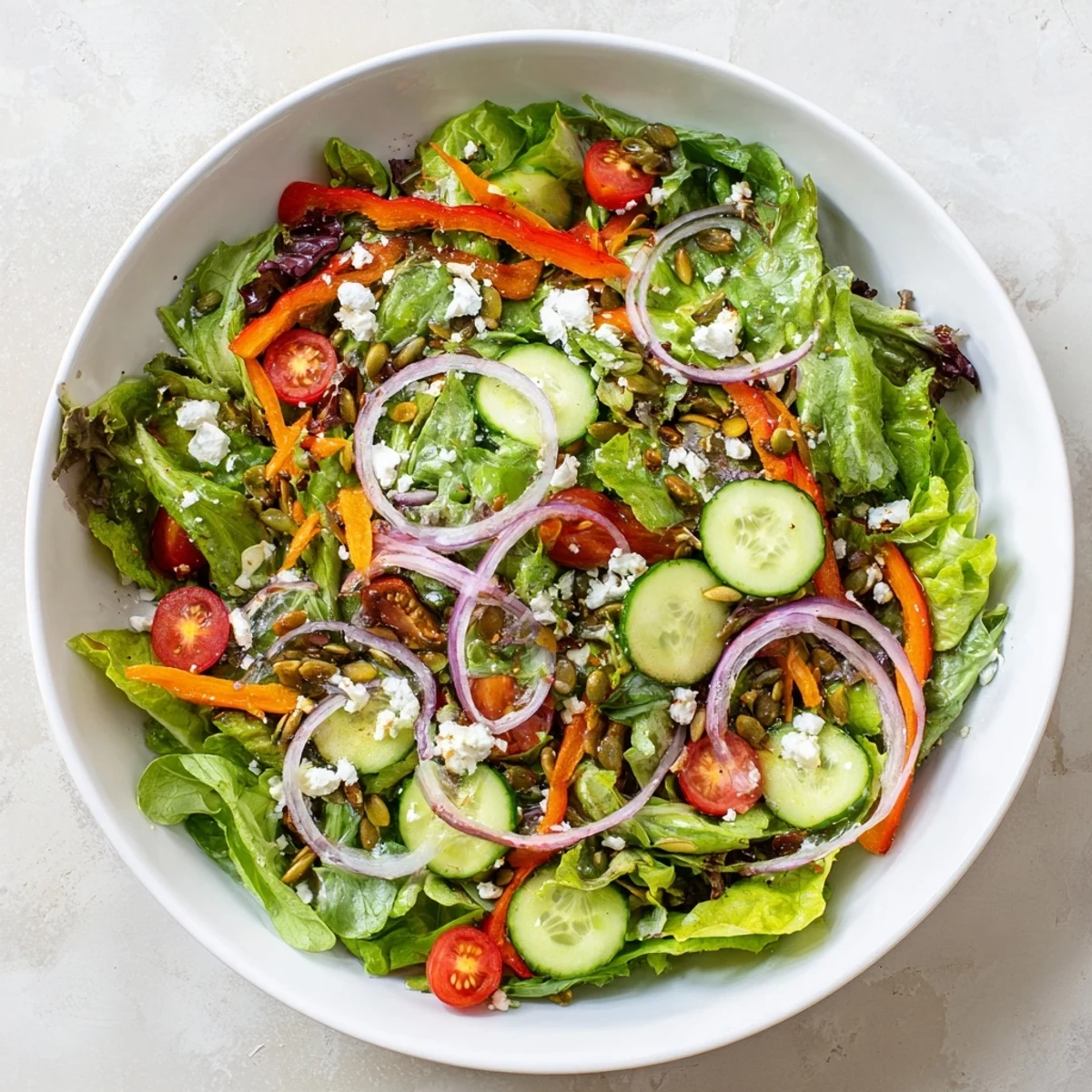 Fresh garden salad with vibrant seasonal vegetables including shredded carrots, bell peppers, and red onion tossed in olive oil vinaigrette
