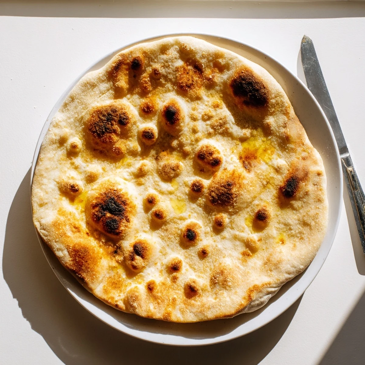 Soft pillowy Turkish Bazlama bread brushed with melted butter and stacked warm on a kitchen towel
