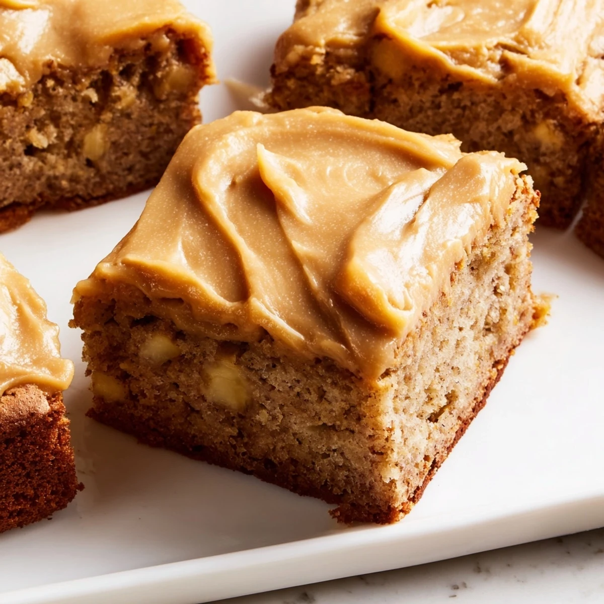 Homemade banana bread brownies featuring thick brown butter frosting and soft fudgy texture with visible banana flecks
