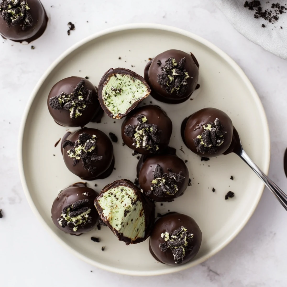 Bite-sized mint Oreo truffles coated in glossy dark chocolate with crushed cookie sprinkles on top