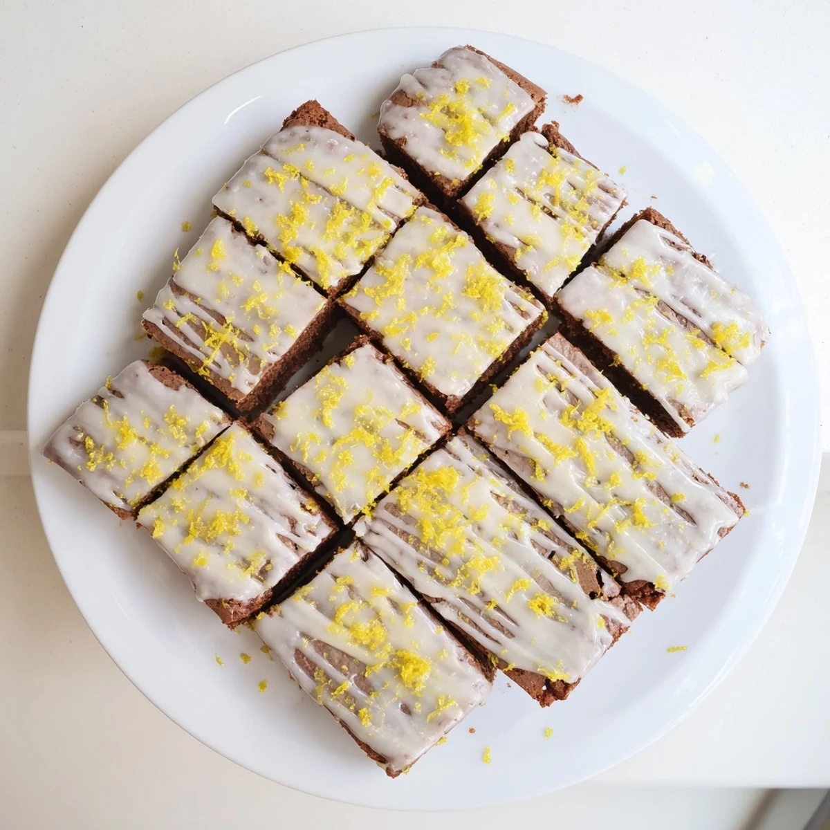 Fudgy lemon zest buttery brownies cut into squares topped with zesty lemon drizzle and zest sprinkles