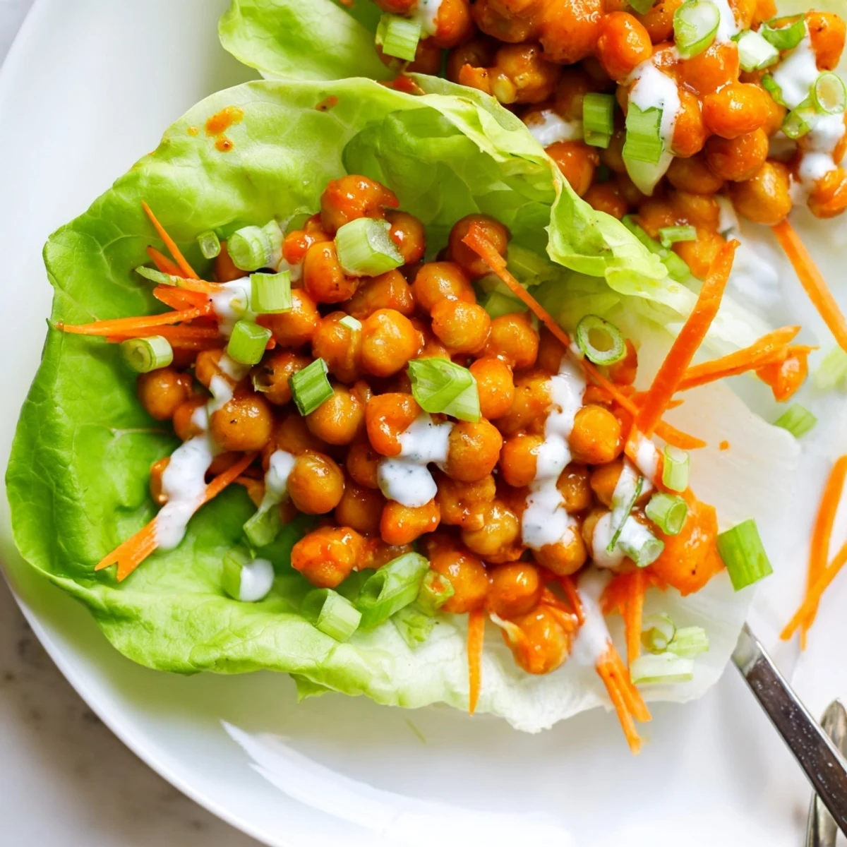 Close-up Buffalo Chickpea Lettuce Wraps garnished with shredded carrots and celery