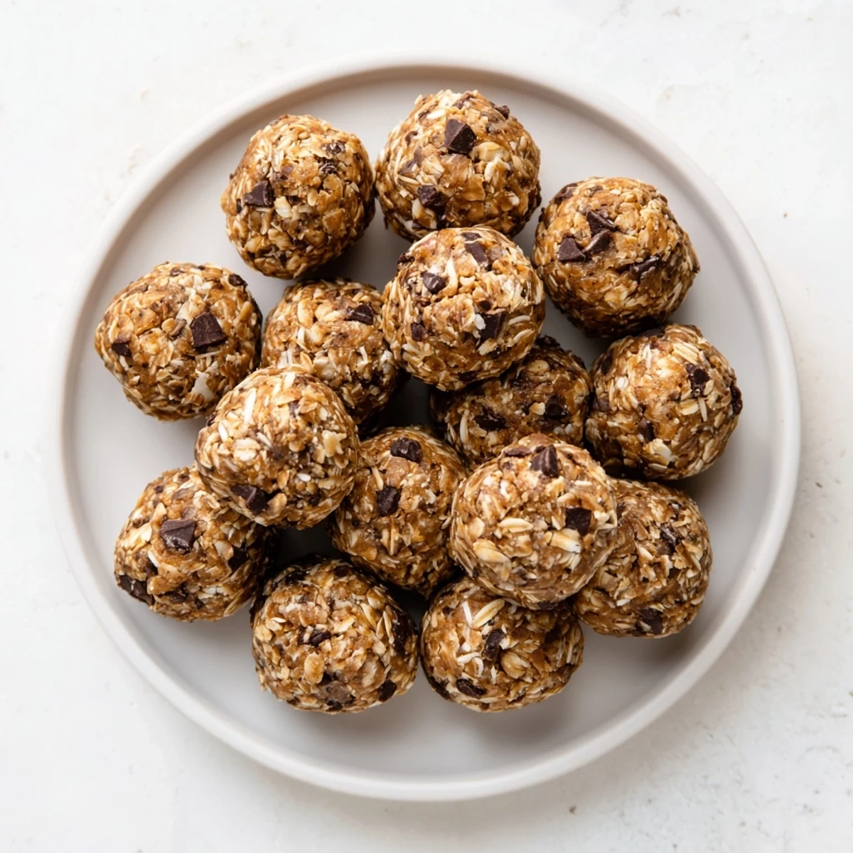 Homemade no bake energy balls rolled into round bites surrounded by oat mixture