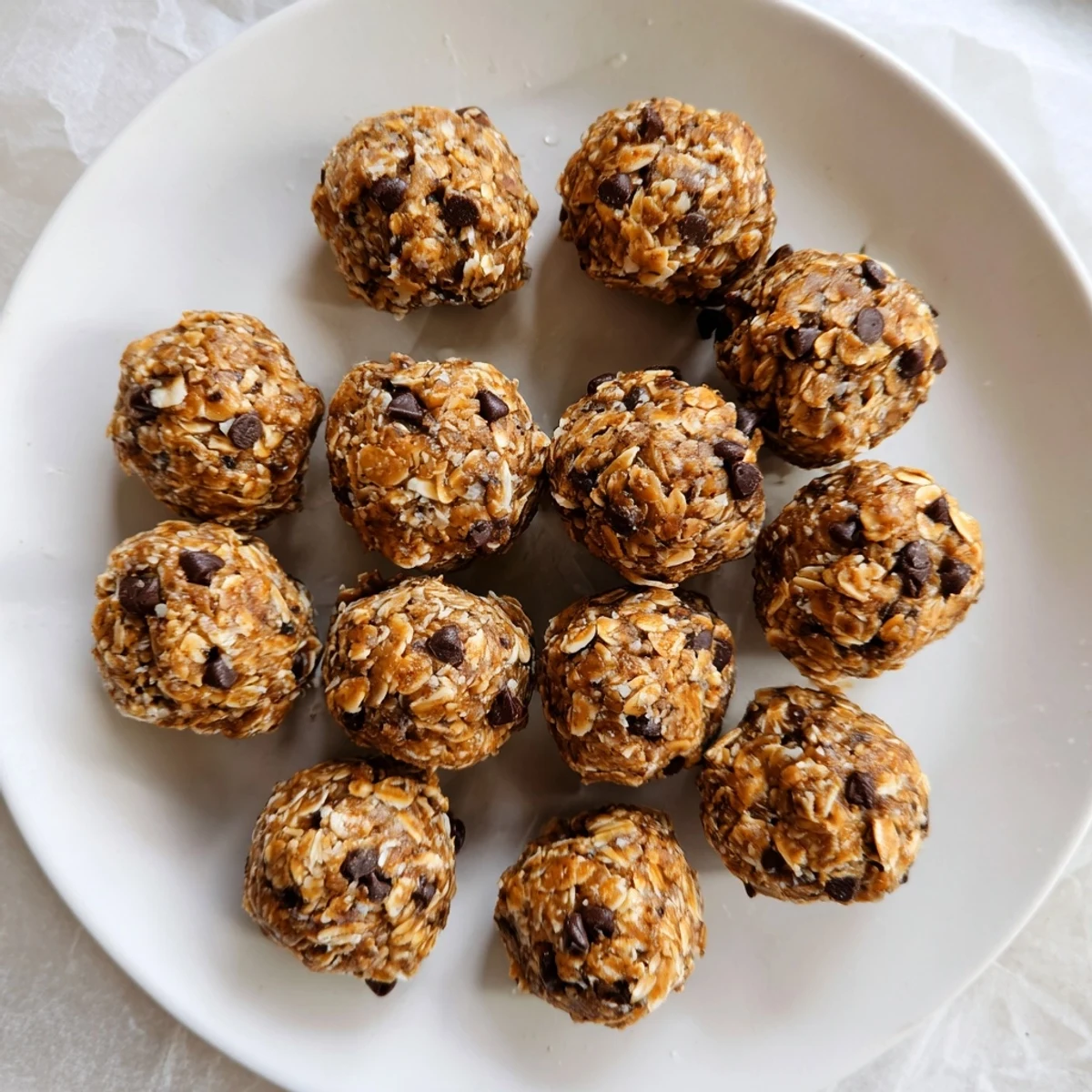 Golden no bake energy balls studded with dark chocolate chips on a white plate