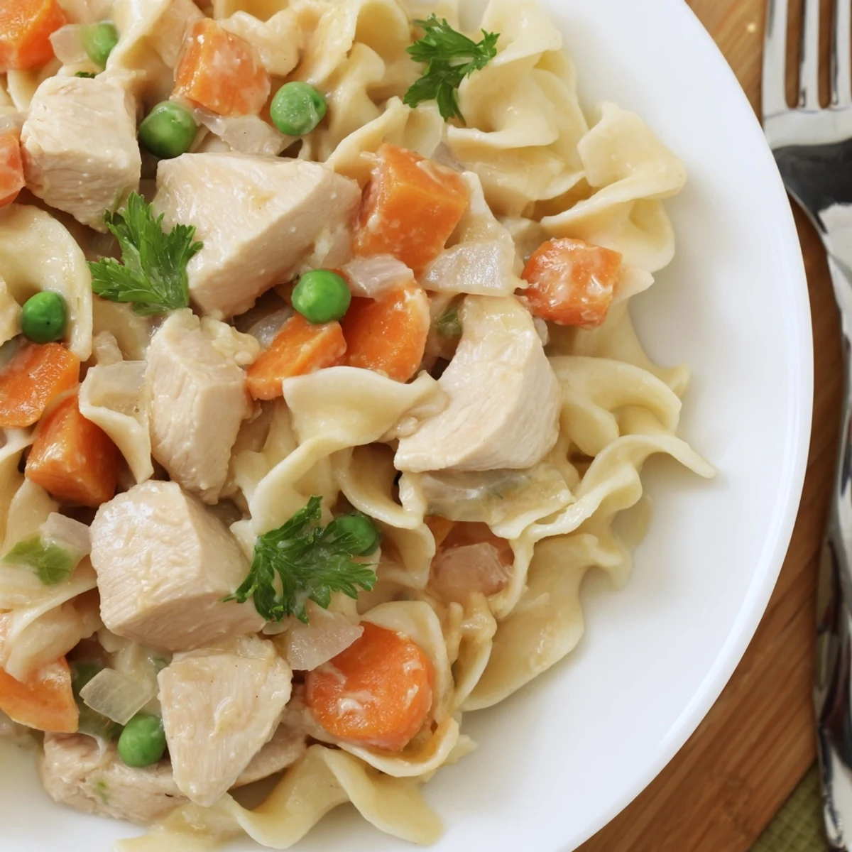Hearty one pot chicken and noodles featuring juicy chicken pieces, colorful carrots, and wide egg noodles in creamy broth