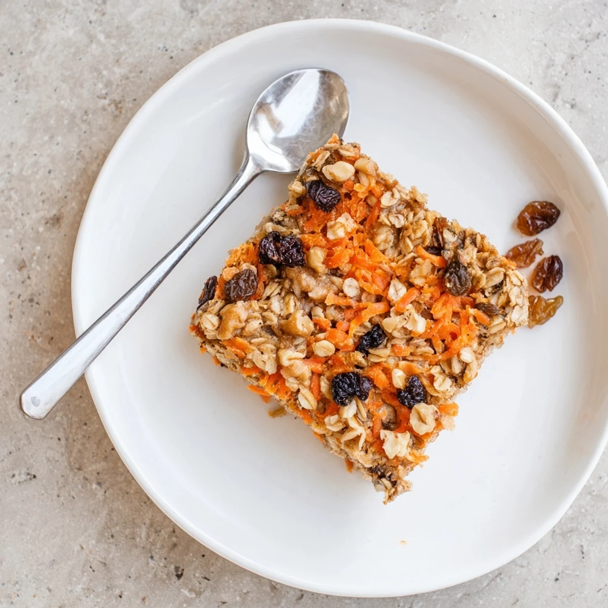 Golden brown carrot cake baked oatmeal topped with walnuts and raisins in a square baking dish