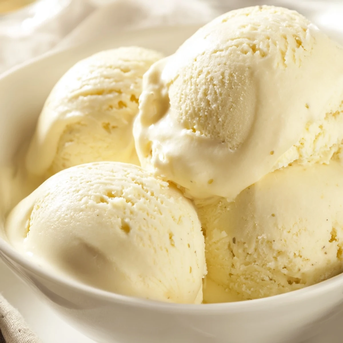 Creamy homemade vanilla ice cream scooped into a chilled glass bowl, ready for dessert
