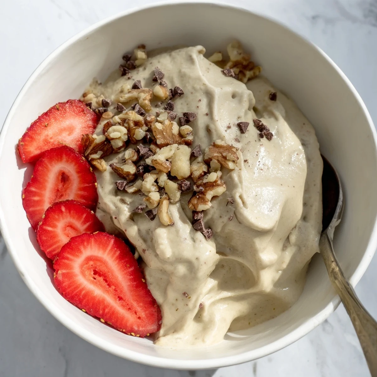 Smooth healthy nice cream bowl with chopped nut topping and fruit garnish