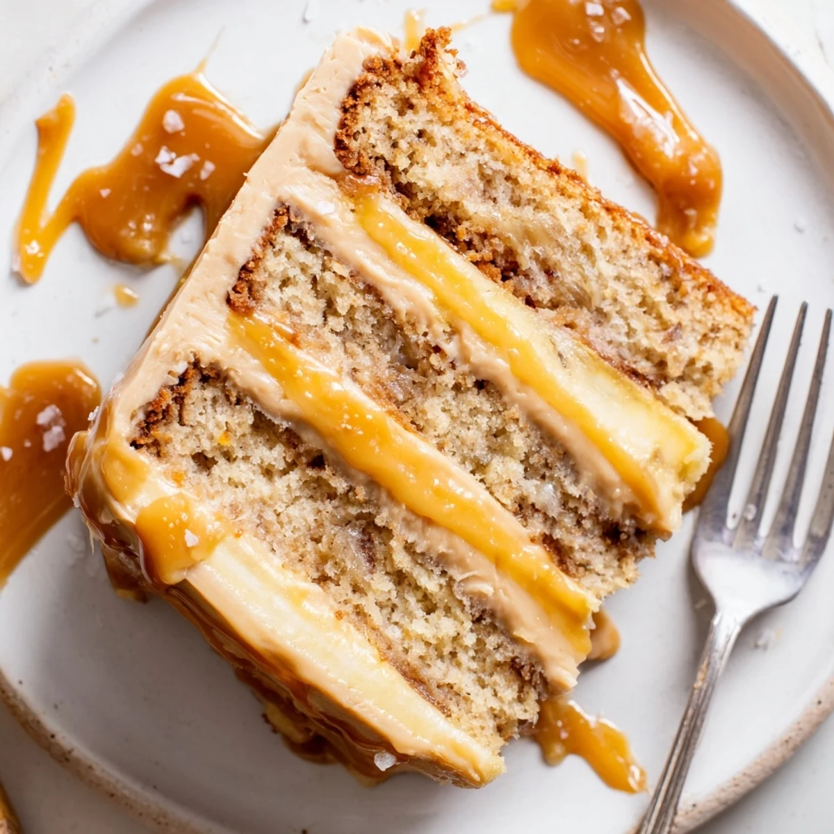 Two-layer salted caramel brown butter banana cake topped with glossy caramel frosting and sea salt