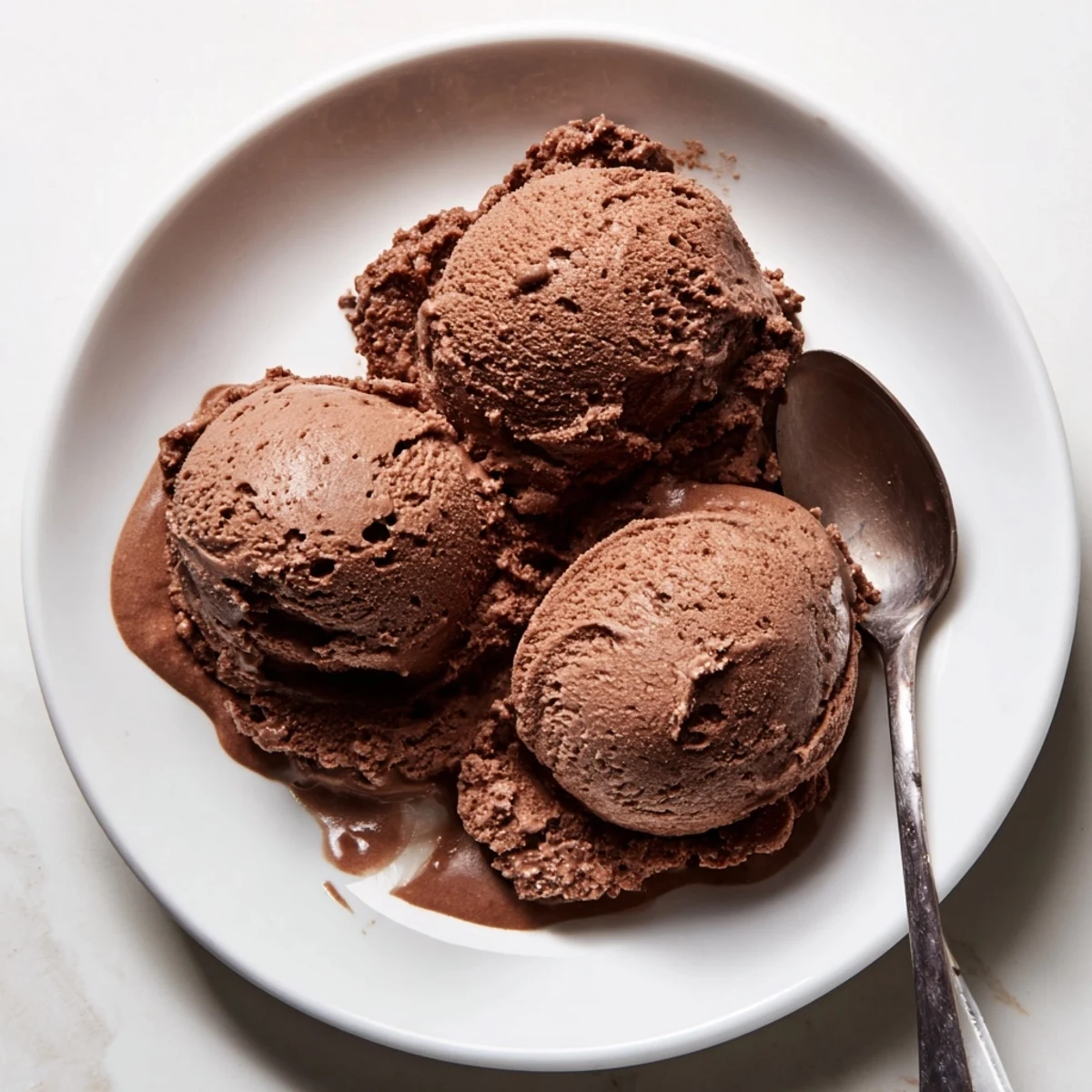 Homemade chocolate sourdough ice cream garnished with fresh raspberries and sea salt flakes on a wooden board