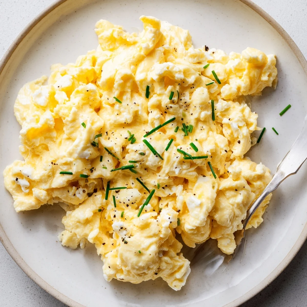 Bright Cottage Cheese Scrambled Eggs with Chives, buttery skillet, flecks of green.