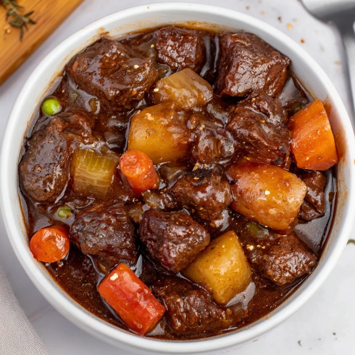 Slow-simmered Beef Stew ladled over buttered noodles, tender beef and carrots
