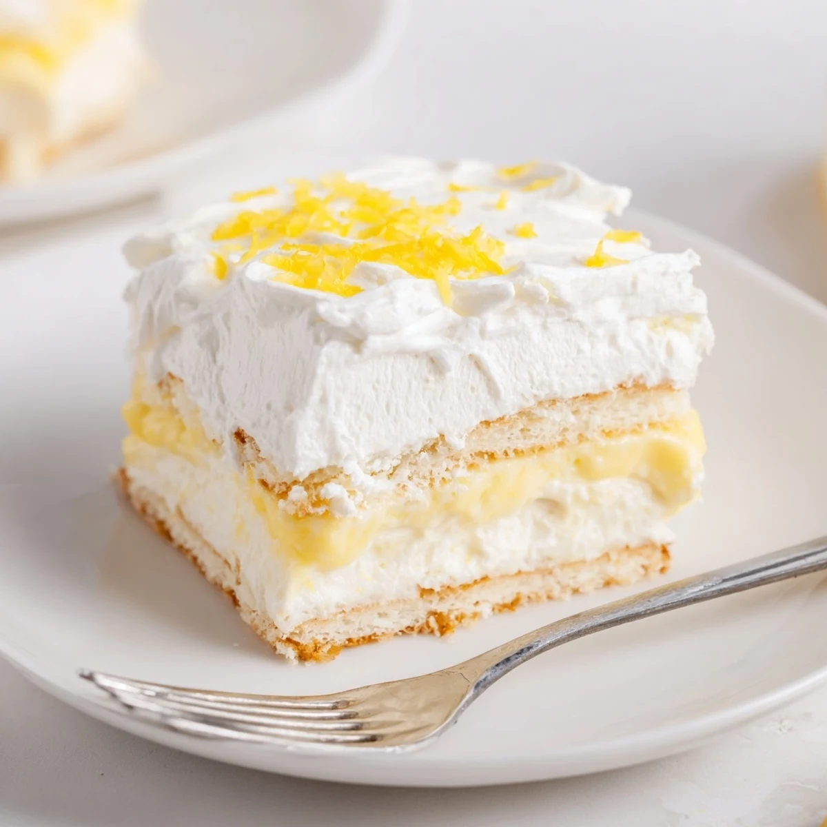 Golden square of Lemon Lush Cake with creamy layers and fluffy white whipped topping