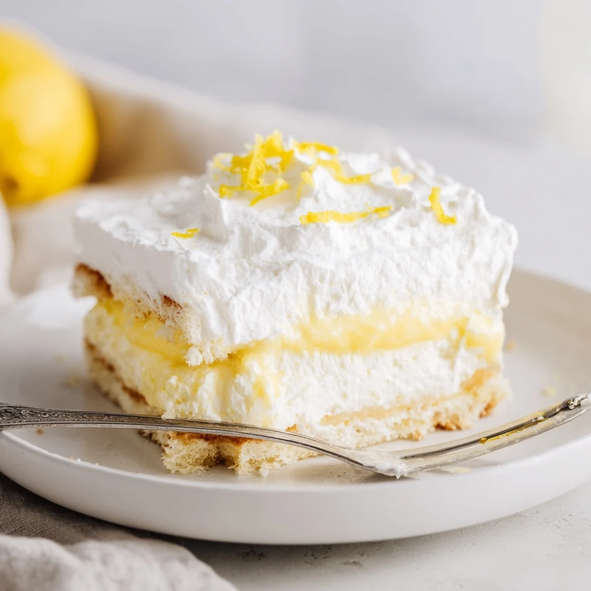 Layered Lemon Lush Cake dessert with bright lemon filling garnished with fresh zest