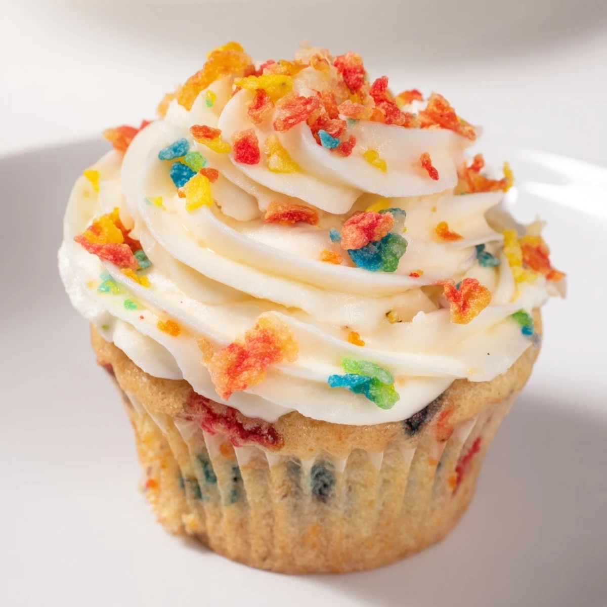 Vibrant rainbow frosting speckled with crunchy Fruity Pebbles cereal piped high on a chocolate cupcake