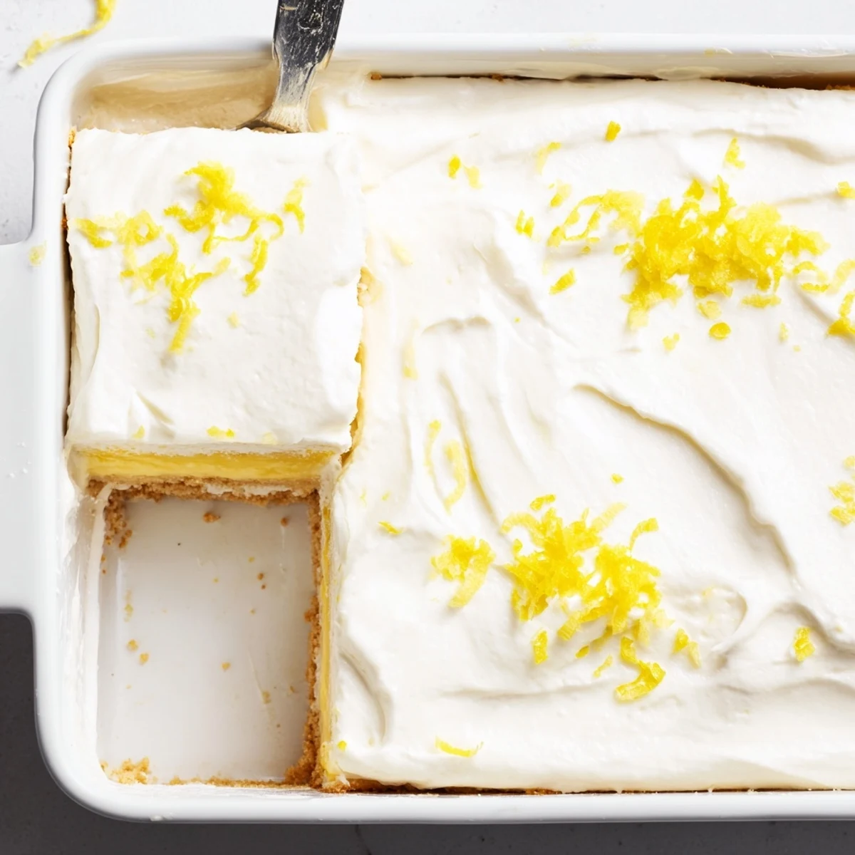 Slice of Lemon Lush Cake showing layered cream, tangy lemon, paired with tea