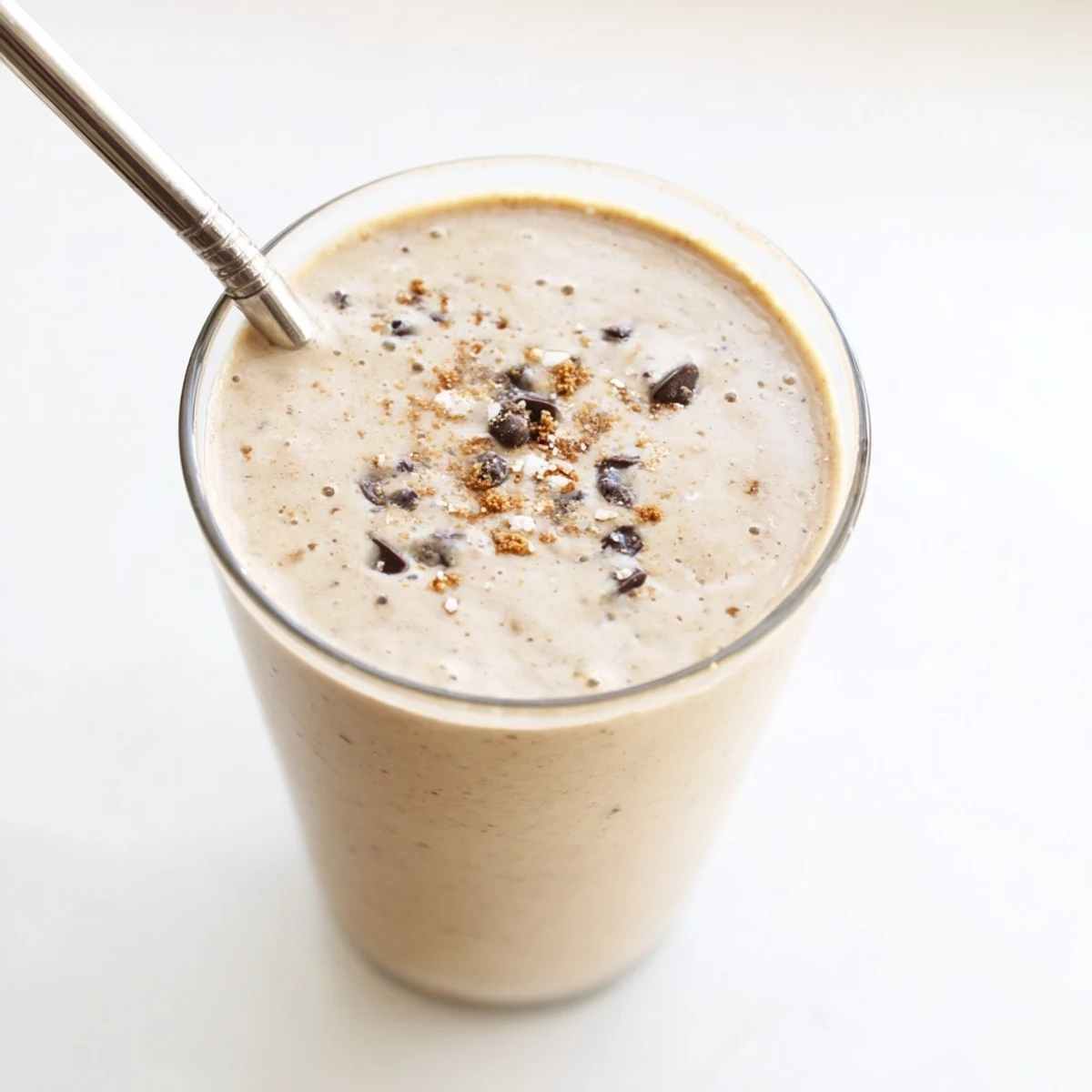 Thick oatmeal cookie dough protein smoothie topped with mini chocolate chips in a glass