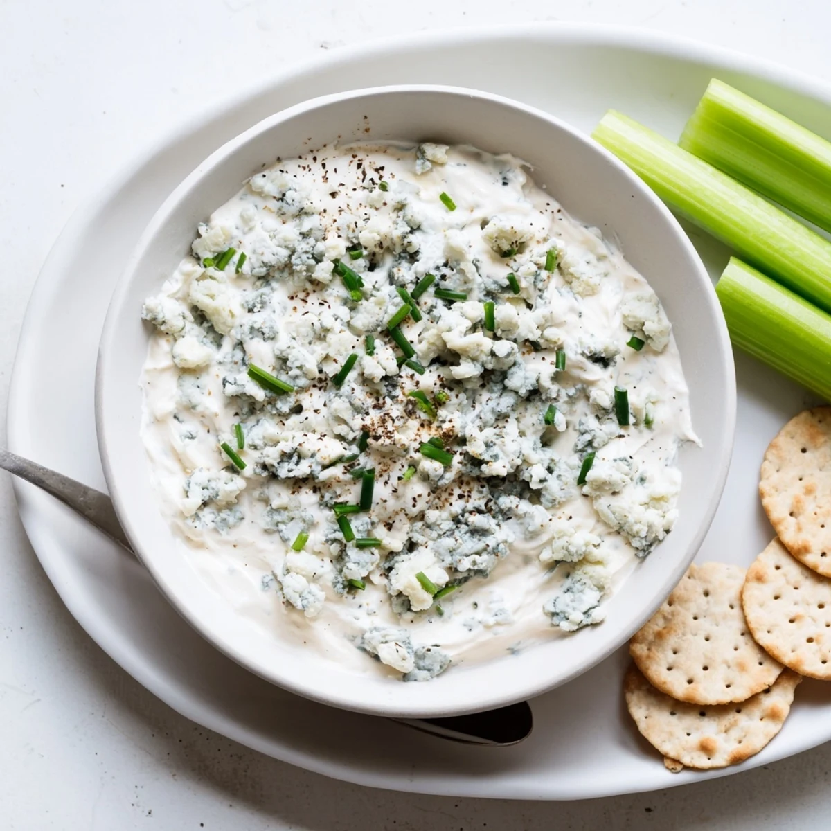 Smooth and tangy blue cheese dip scooped up with crispy crackers on a rustic board