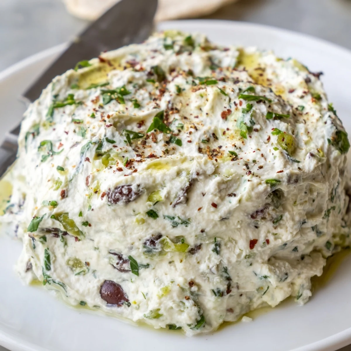 Rustic bowl of Italian Style Olive and Cheese Spread garnished with parsley