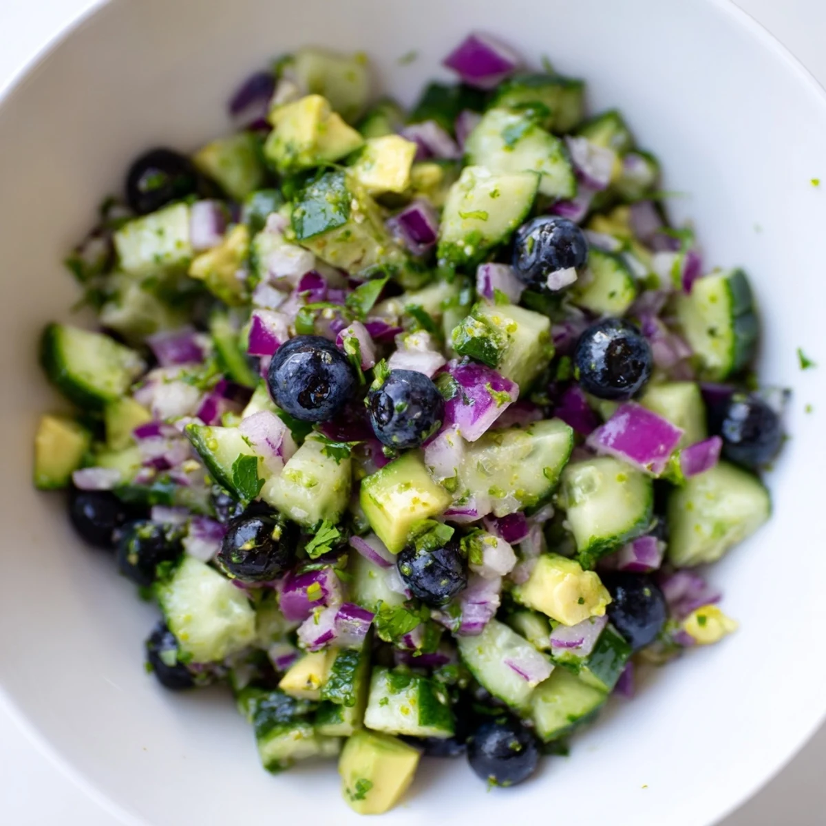 Vibrant blueberry cucumber salsa with diced avocado and red onion served in a rustic dish