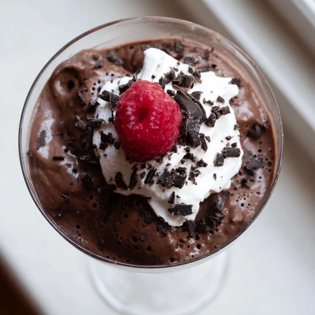 Creamy chocolate mousse spooned into dessert cups dusted with cocoa powder