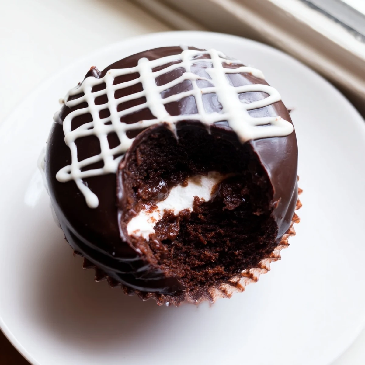 Homemade Hostess Cupcakes with glossy ganache and signature white swirl on top