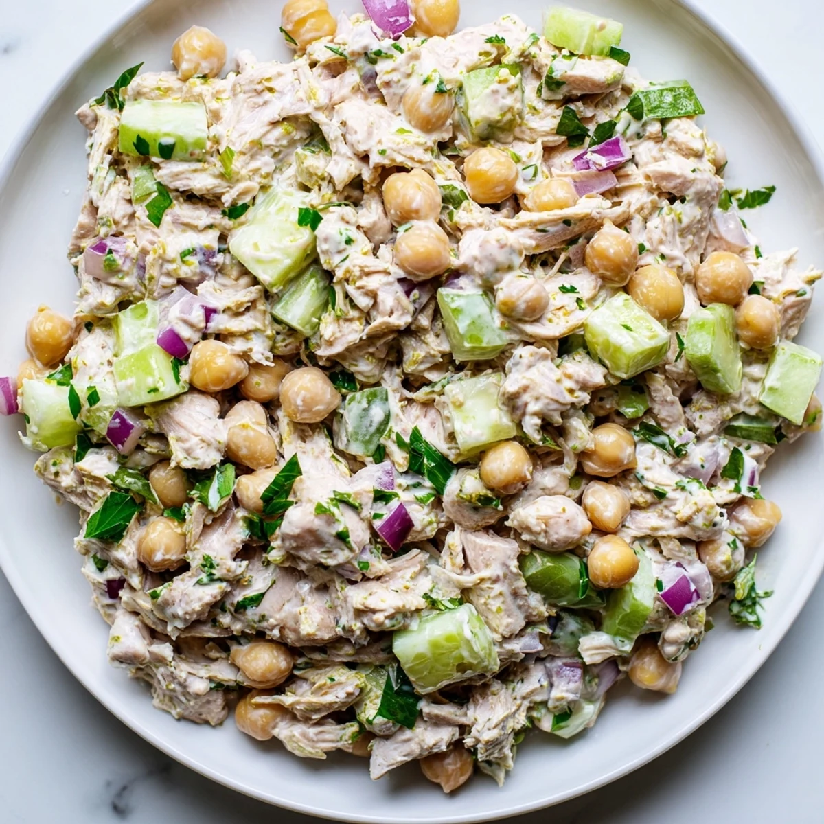 A close-up of creamy tuna chickpea cucumber salad spooned onto crisp lettuce leaves