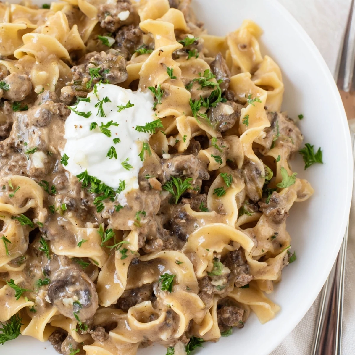 Creamy hamburger stroganoff served over tender egg noodles with fresh parsley garnish