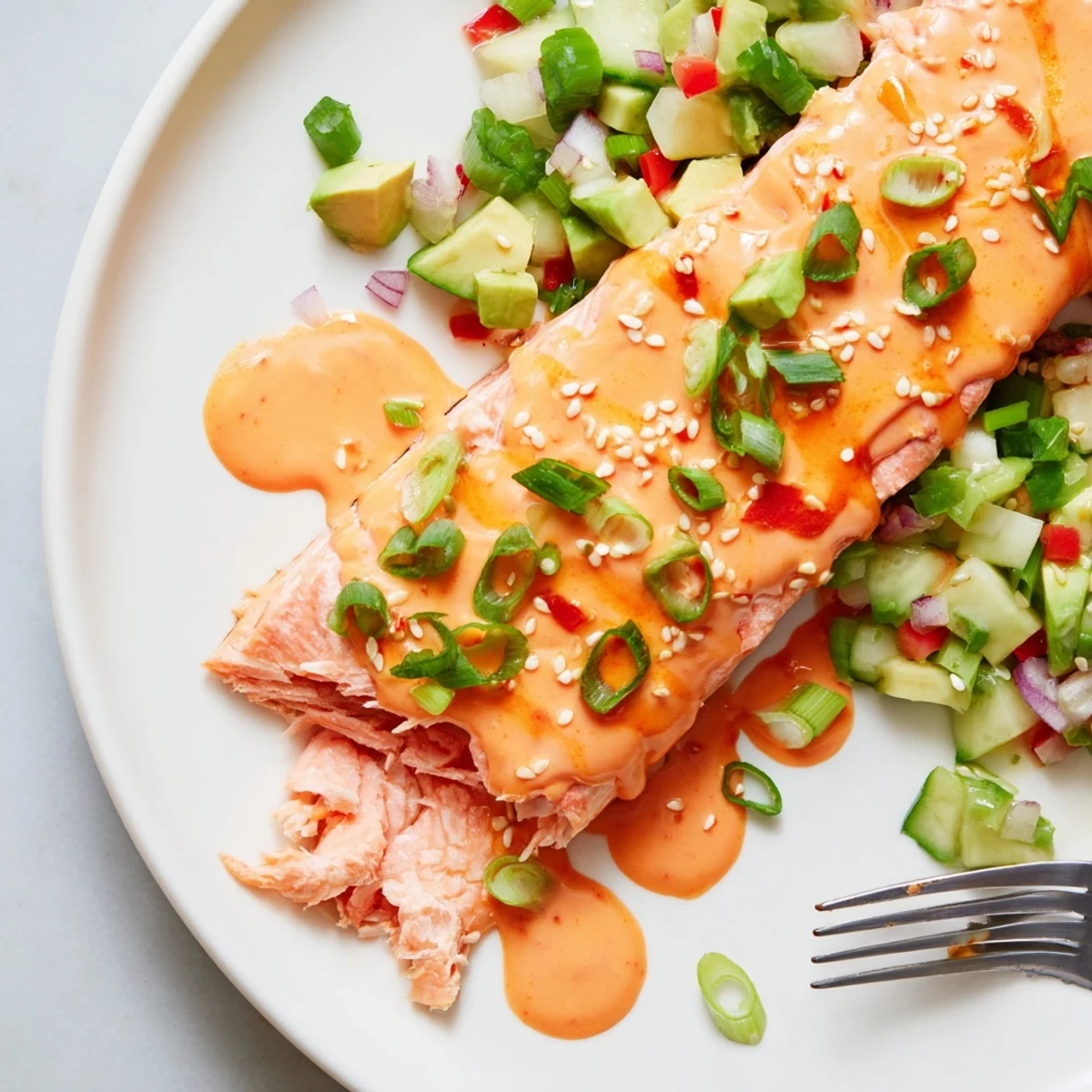 Golden pan-seared Bang Bang Salmon topped with creamy Sriracha sauce over a cool avocado cucumber salsa.