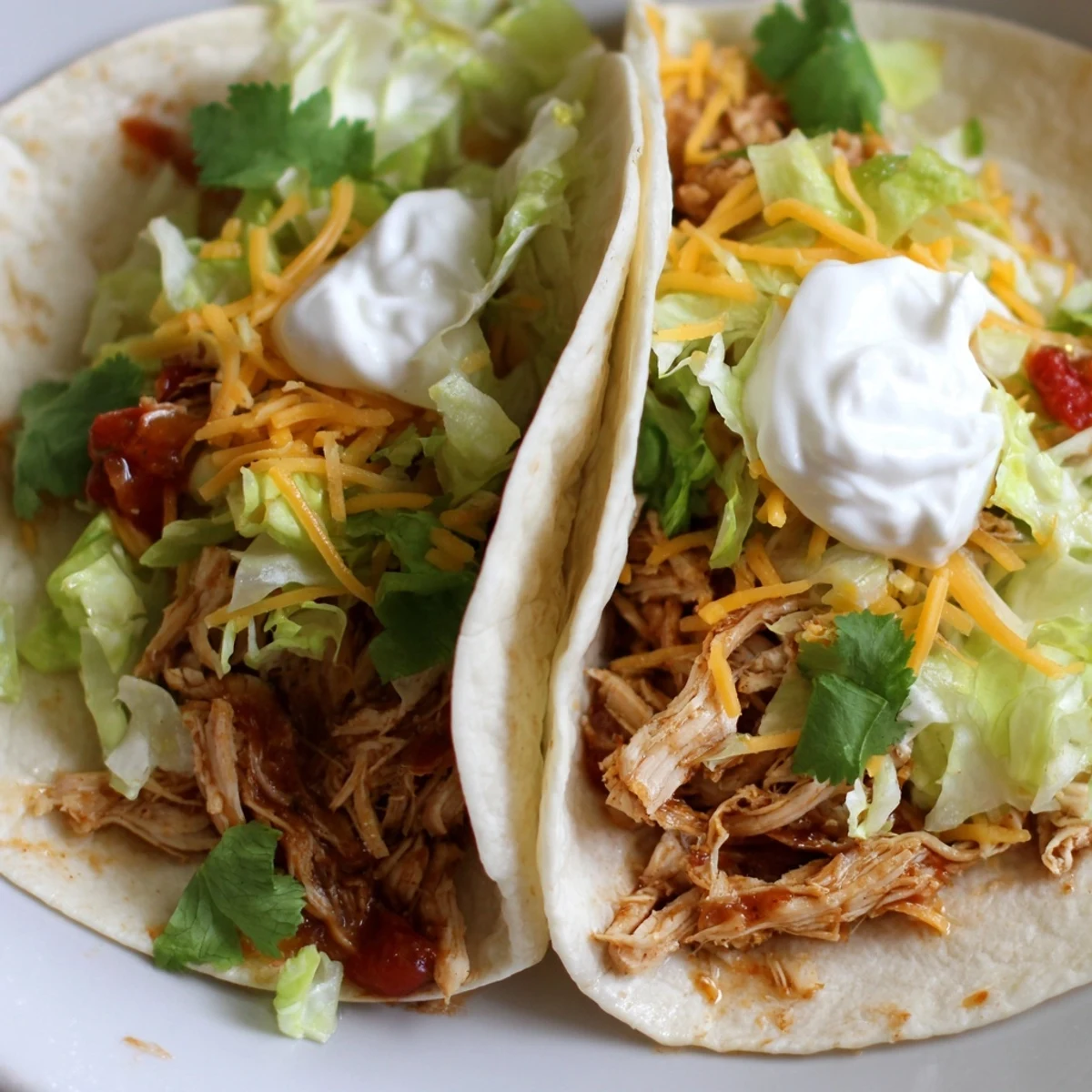 Juicy shredded Slow Cooker Ranch Chicken Tacos topped with sour cream and crisp lettuce