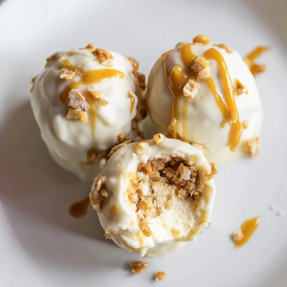 Bite-sized salted caramel pretzel cheesecake balls garnished with crushed pretzels and flaky sea salt