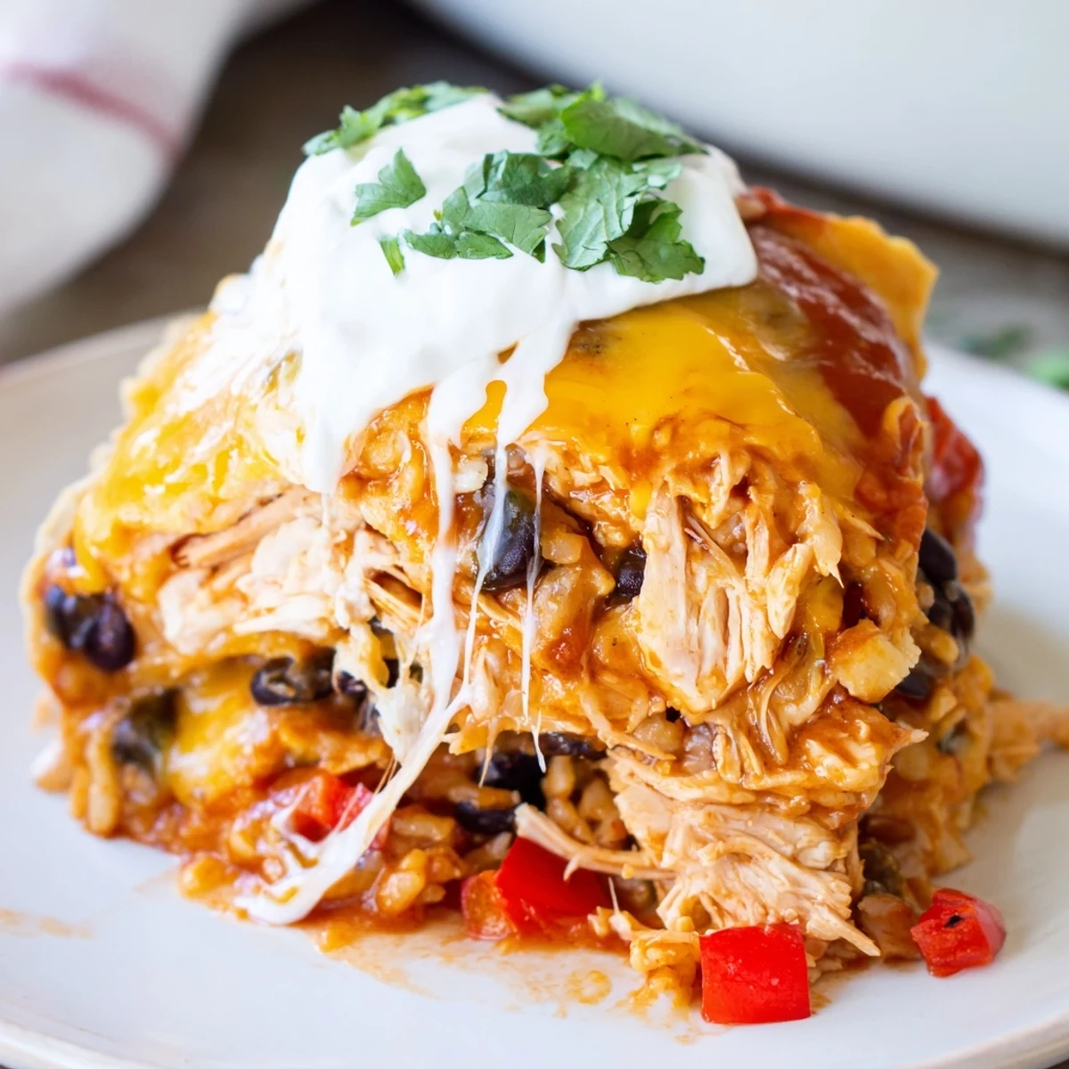 Layered chicken burrito casserole with tender shredded meat, black beans, and gooey melted cheese