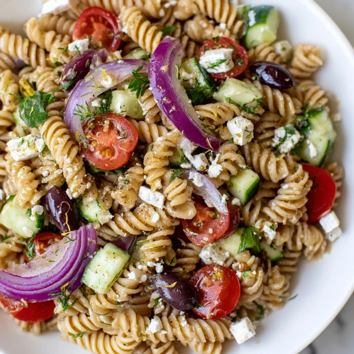 Fresh Greek Pasta Salad in a bowl with cherry tomatoes and herbed dressing