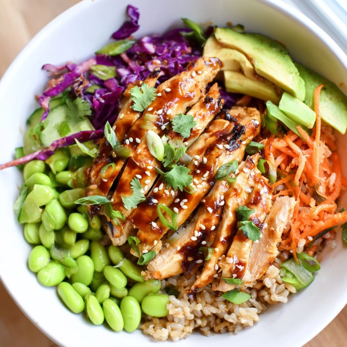A colorful Asian Inspired Chicken Power Bowl topped with sesame seeds, avocado, and crisp vegetables.