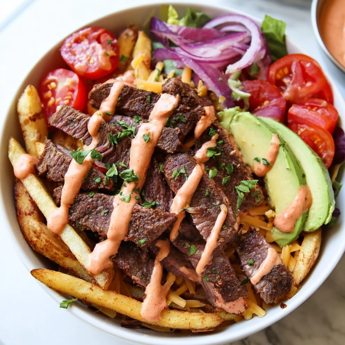 Steak strips crispy fries bowl topped with fresh avocado and tomatoes