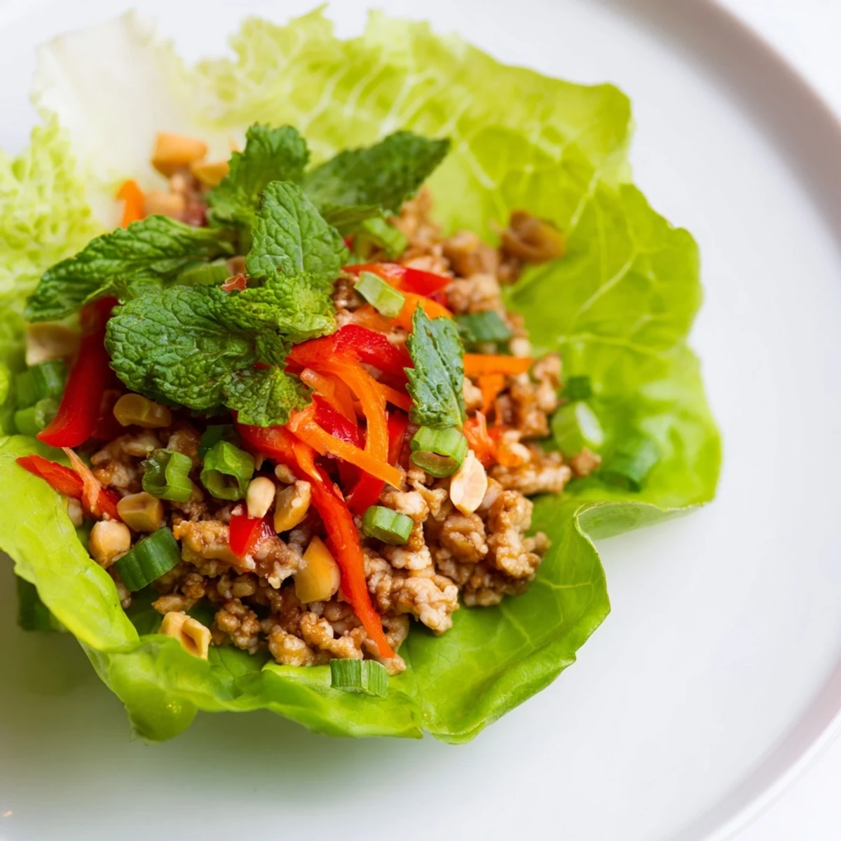 Golden brown Thai Chicken Lettuce Wraps served with lime wedges and cool lettuce