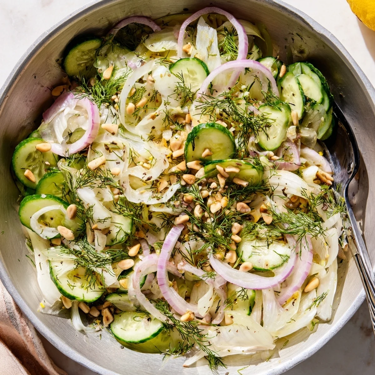 Refreshing crisp fennel cucumber salad garnished with lemon zest and toasted pine nuts