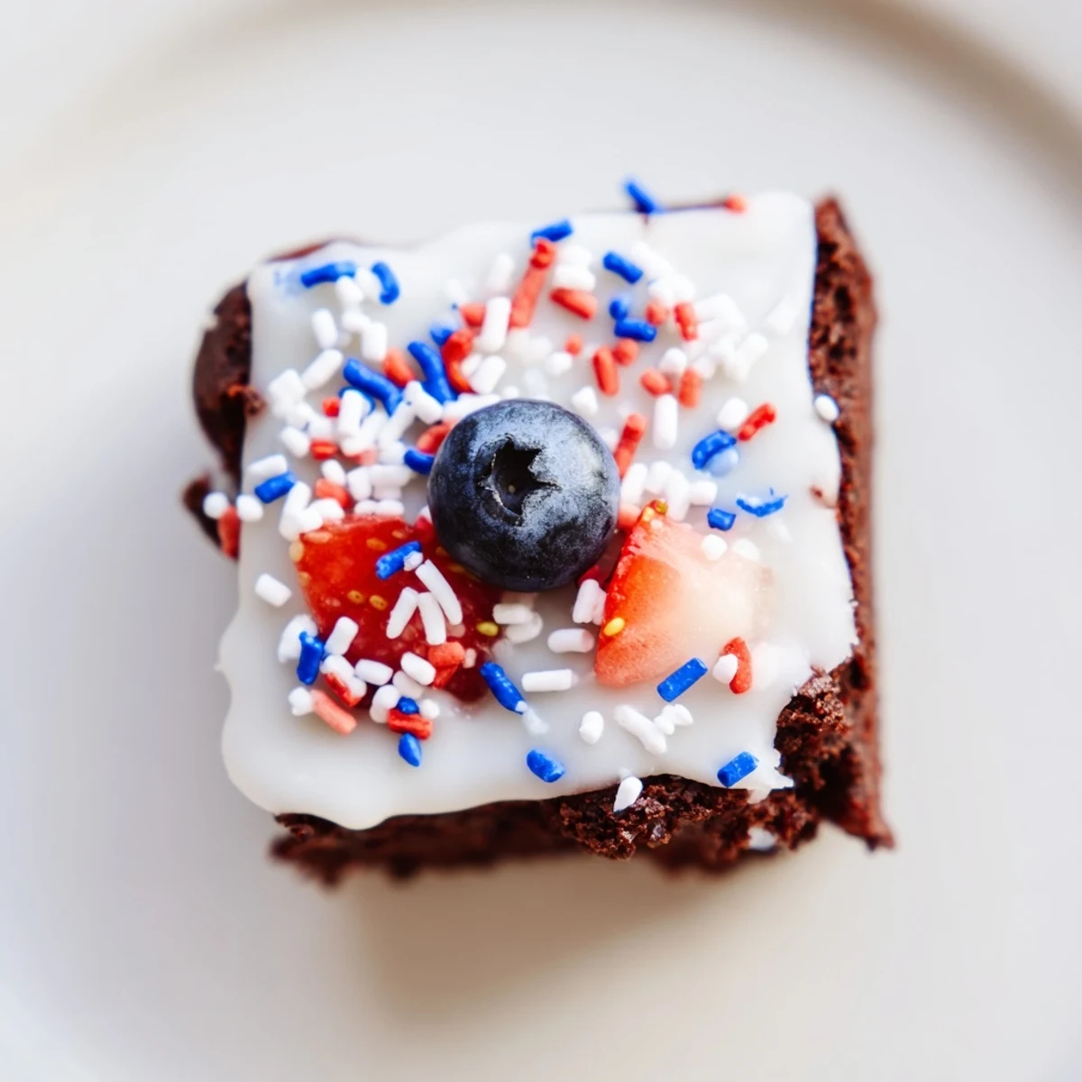 Bite-sized brownie bites glazed with white icing and colorful Fourth of July decorations for summer parties.