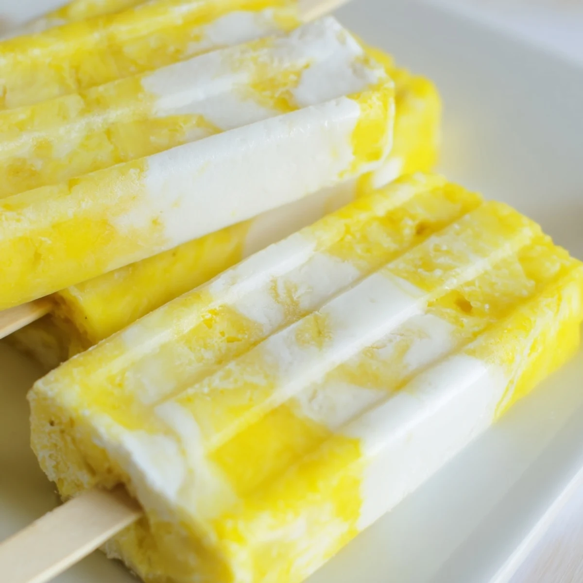 Creamy vegan Pineapple Coconut Lime Popsicles ready to enjoy on a sunny afternoon.