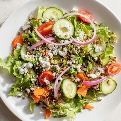 Spring Mix Salad with Vinaigrette drizzled over vibrant greens, carrots, and red onion in a bowl.