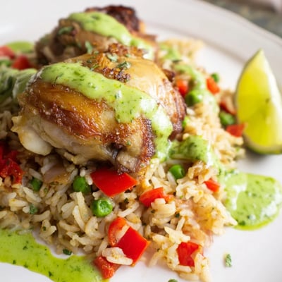 Juicy chicken thighs nestled in fluffy cilantro rice topped with creamy zesty Peruvian green sauce and bright lime