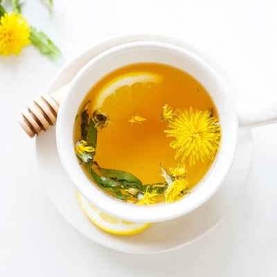 Warm herbal dandelion tea infusion garnished with lemon slice on wooden table