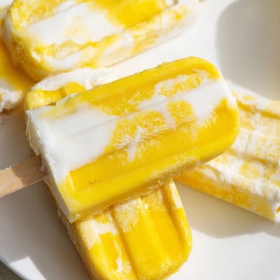 Tropical Pineapple Coconut Lime Popsicles glistening with fresh fruit zest on a hot day.