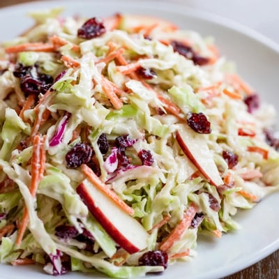 Fresh cranberry apple coleslaw topped with nuts, perfect for a refreshing side dish.